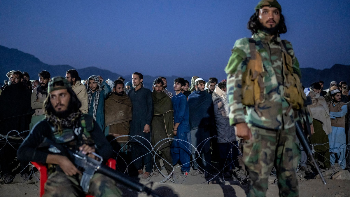 Taliban-Kämpfer stehen Wache, während afghanische Flüchtlinge in einem Lager nahe der pakistanisch-afghanischen Grenze anstehen, um sich registrieren zu lassen. - Foto: Ebrahim Noroozi/AP/dpa