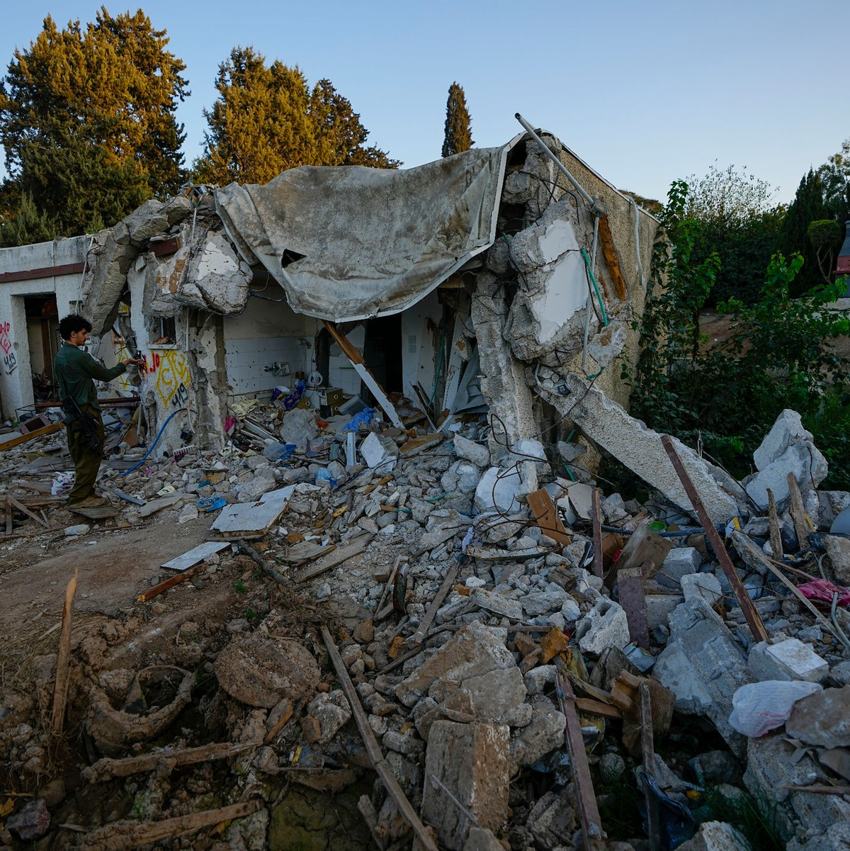 Ein israelischer Soldat inspiziert ein von Hamas-Kämpfern beschädigtes Haus im Kibbuz Kfar Azza. - Foto: Ariel Schalit/AP/dpa