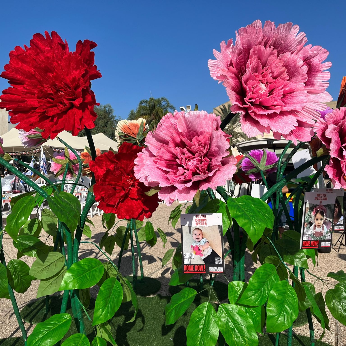 Blumen mit Bildern von Kindern, die seit dem Massaker der Hamas im israelischen Grenzgebiet am 07. Oktober als Geiseln gehalten und vermisst werden, stehen vor dem Kunstmuseum in Tel Aviv. - Foto: Sara Lemel/dpa