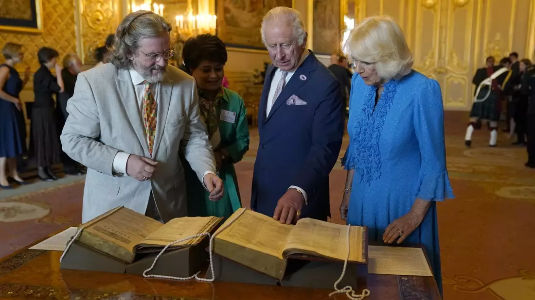 König Charles III. und Königin Camilla betrachten das erste Shakespeare-Folio während eines Empfangs auf Schloss Windsor. - Bild: Andrew Matthews/PA Wire/dpa