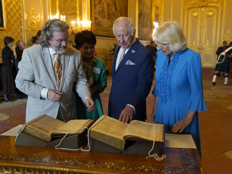 König Charles III. und Königin Camilla betrachten das erste Shakespeare-Folio während eines Empfangs auf Schloss Windsor. - Foto: Andrew Matthews/PA Wire/dpa