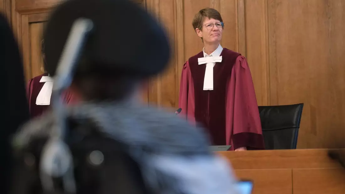 Renate Philipp, Versitzende Richterin am Bundesverwaltungsgericht, steht während der Verhandlung im Gerichtssaal in Leipzig. Im Vordergrund sitzt einer Kläger im Rollstuhl. - Bild: Sebastian Willnow/dpa