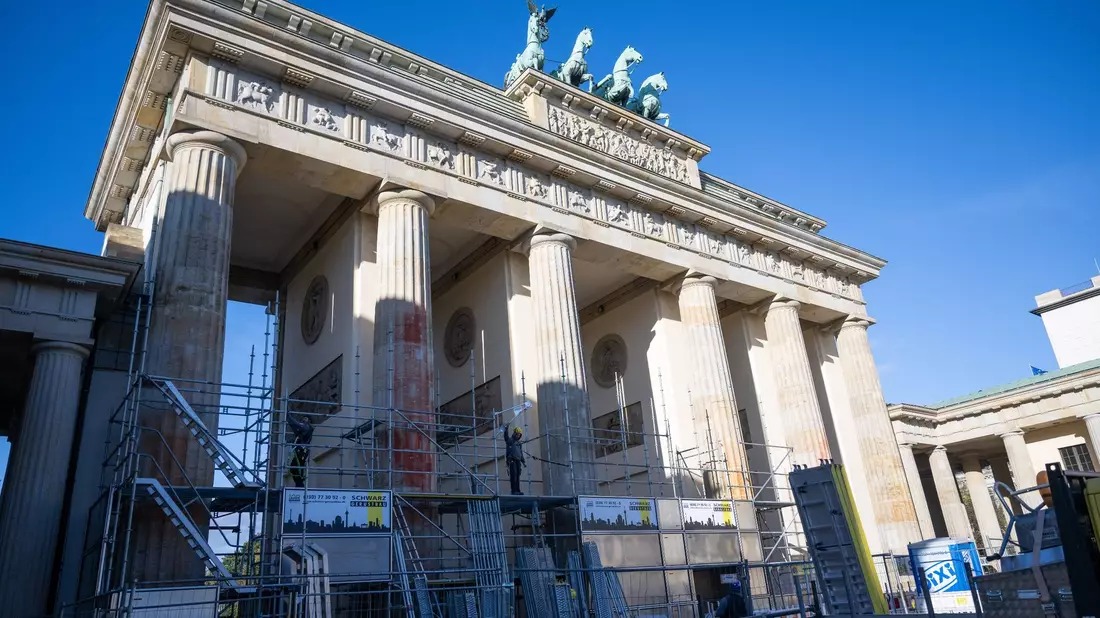 Auf einer Seite des Brandenburger Tors wird ein Baugerüst aufgebaut, um die Folgen der Farbattacke zu beseitigen. - Bild: Christophe Gateau/dpa