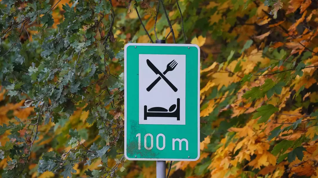 Ein Schild weist auf die Möglichkeit zum Essen und Übernachten hin: Die Übernachtungszahlen steigen. - Bild: Soeren Stache/dpa