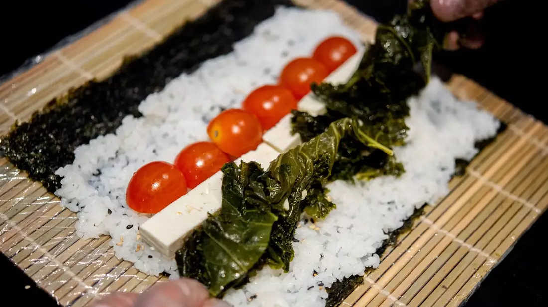 Ein Koch bereitet in der Küche des Restaurants Moto Kitchen Sushi mit Grünkohl, Tomaten und Feta zu. - Bild: Hauke-Christian Dittrich/dpa