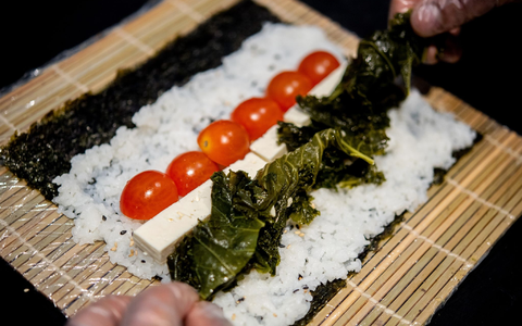 Ein Koch bereitet in der Küche des Restaurants Moto Kitchen Sushi mit Grünkohl, Tomaten und Feta zu. - Foto: Hauke-Christian Dittrich/dpa