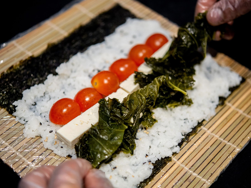 Ein Koch bereitet in der Küche des Restaurants Moto Kitchen Sushi mit Grünkohl, Tomaten und Feta zu. - Foto: Hauke-Christian Dittrich/dpa