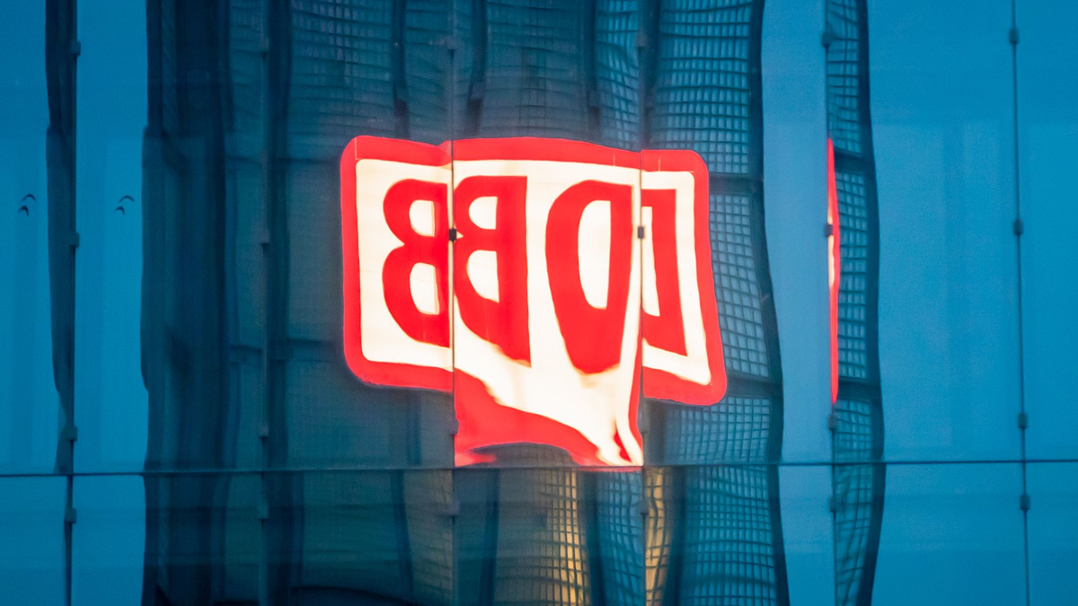 Das Logo der Deutschen Bahn AG (DB) am Berliner Hauptbahnhof spiegelt sich am Morgen in einer Gebäudefassade. - Foto: Christoph Soeder/dpa
