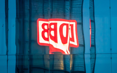 Das Logo der Deutschen Bahn AG (DB) am Berliner Hauptbahnhof spiegelt sich am Morgen in einer Gebäudefassade. - Foto: Christoph Soeder/dpa