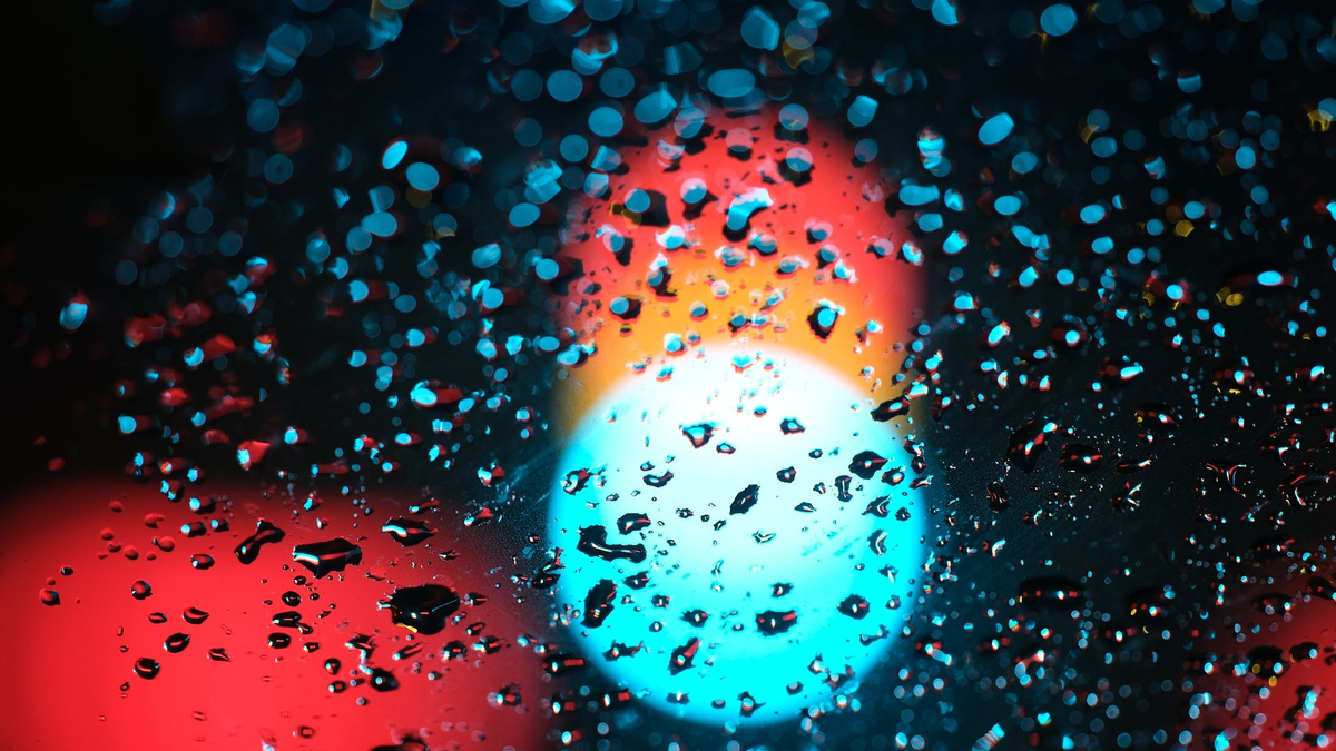 Eine Ampel hinter einer regennassen Scheibe eines Autos. - Foto: Sebastian Willnow/dpa