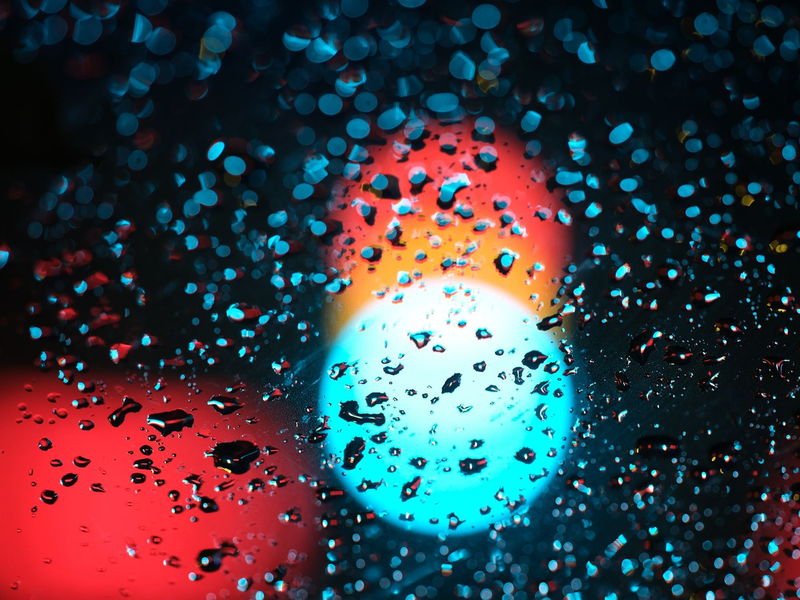 Eine Ampel hinter einer regennassen Scheibe eines Autos. - Foto: Sebastian Willnow/dpa