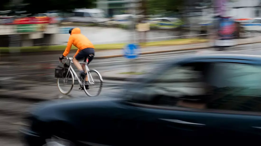 Ein Pkw fährt hinter einem Fahrradfahrer an einer Kreuzung einer Hauptverkehrsstraße in Berlin. Inwieweit Maßnahmen zur Verbesserung der Verkehrssicherheit befürwortet werden, hängt auch stark vom Alter ab. - Bild: Carsten Koall/dpa