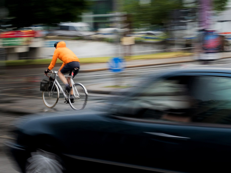 Ein Pkw fährt hinter einem Fahrradfahrer an einer Kreuzung einer Hauptverkehrsstraße in Berlin. Inwieweit Maßnahmen zur Verbesserung der Verkehrssicherheit befürwortet werden, hängt auch stark vom Alter ab. - Foto: Carsten Koall/dpa