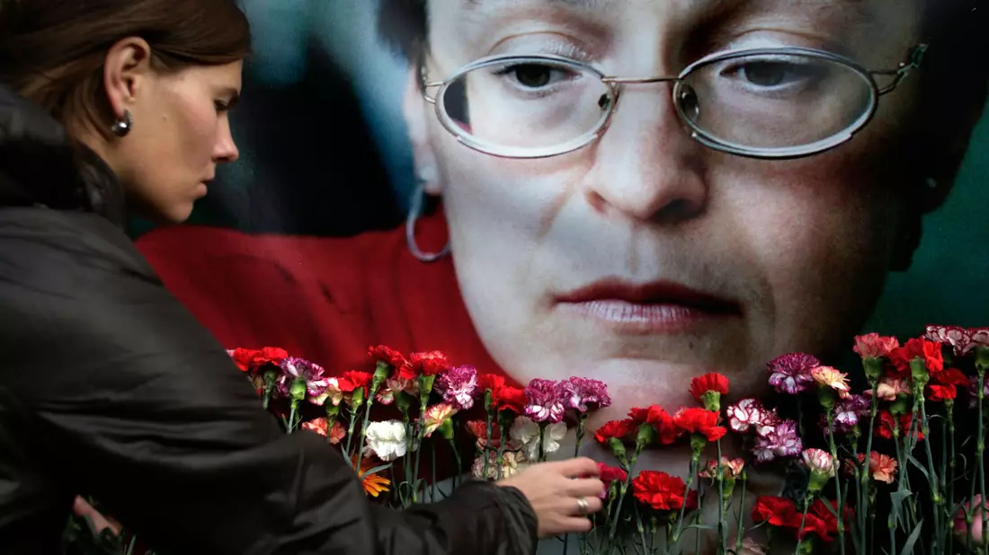 Eine Frau legt in Moskau Blumen vor einem Porträt der ermordeten russischen Journalistin Anna Politkowskaja nieder (Archivbild). - Bild: Pavel Golovkin/AP/dpa