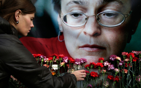Eine Frau legt in Moskau Blumen vor einem Porträt der ermordeten russischen Journalistin Anna Politkowskaja nieder (Archivbild). - Foto: Pavel Golovkin/AP/dpa