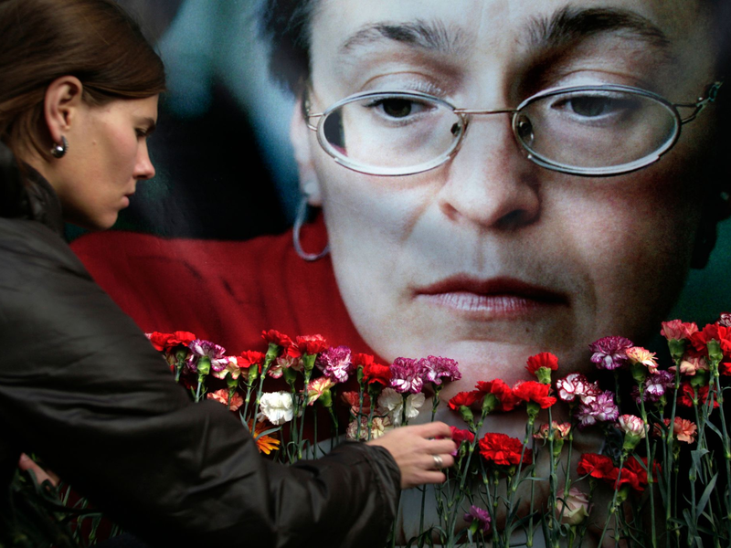Eine Frau legt in Moskau Blumen vor einem Porträt der ermordeten russischen Journalistin Anna Politkowskaja nieder (Archivbild). - Foto: Pavel Golovkin/AP/dpa