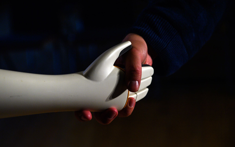 Eine menschliche Hand greift die Hand eines humanoiden Roboters. - Foto: Klaus-Dietmar Gabbert/dpa