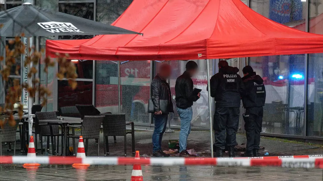 Polizeibeamte untersuchen unter einem Zeltdach den Tatort in Gummersbach. - Bild: Henning Kaiser/dpa