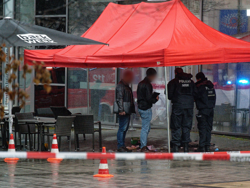 Polizeibeamte untersuchen unter einem Zeltdach den Tatort in Gummersbach. - Foto: Henning Kaiser/dpa