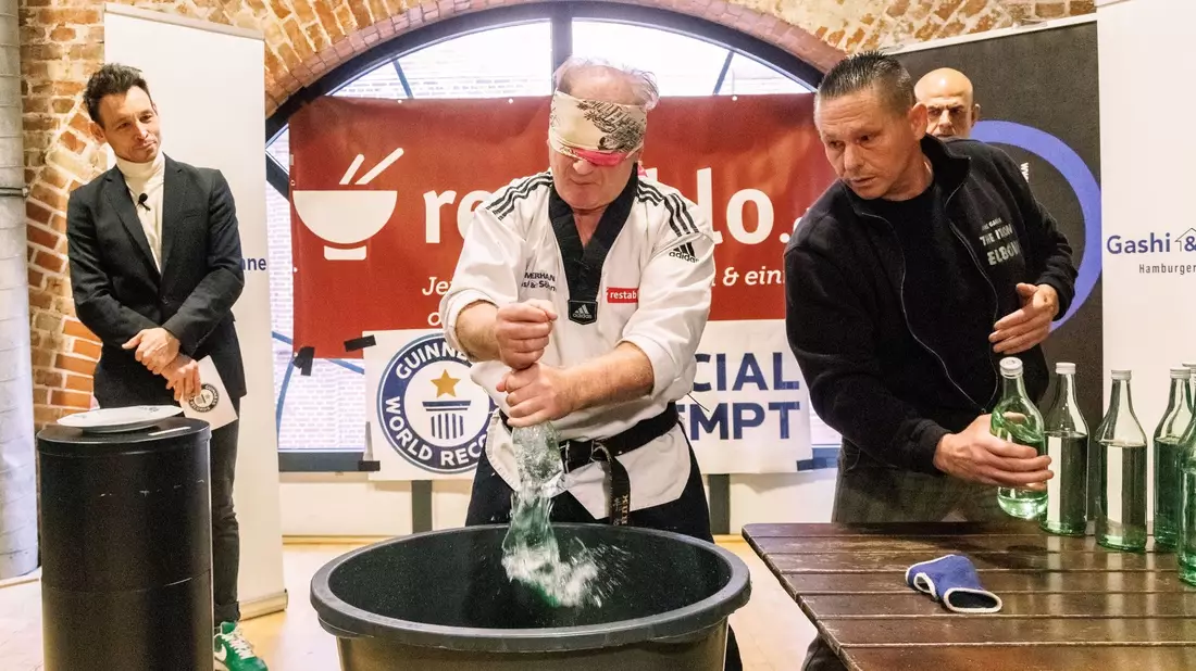 Der Kampfsportler Muhamed Kahrimanovic beim Versuch, mit verbundenen Augen und einem rohen Ei in der Hand Glasflaschen zu zerschlagen. - Bild: Markus Scholz/dpa