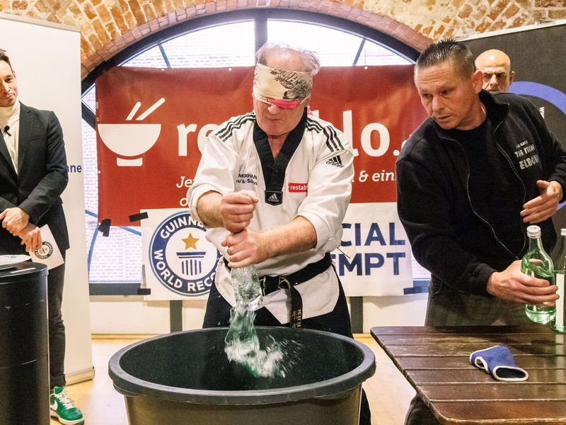 Der Kampfsportler Muhamed Kahrimanovic beim Versuch, mit verbundenen Augen und einem rohen Ei in der Hand Glasflaschen zu zerschlagen. - Foto: Markus Scholz/dpa