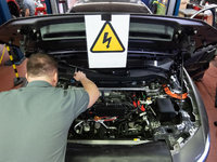 Ein KFZ-Mechaniker wartet ein E-Auto. - Foto: Marijan Murat/dpa