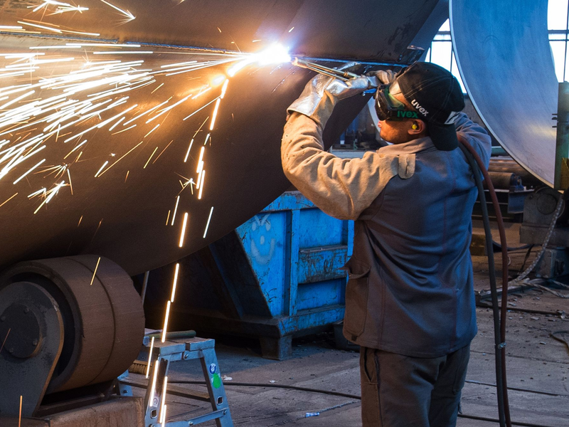 Ein Mann aus Somalia, der zuvor als Schweißer ausgebildet wurde, arbeitet in einer Firma an einem Stahlsegment. - Foto: Patrick Pleul/ZB/dpa
