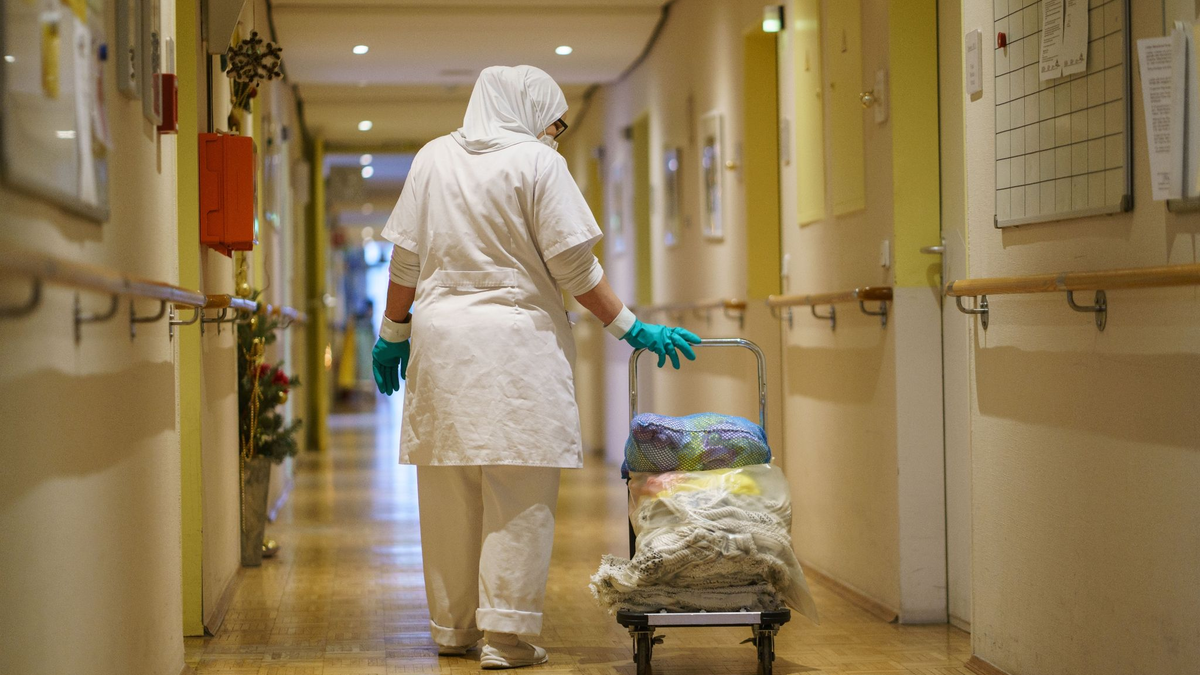 Eine Reinigungskraft zieht einen Wagen mit Wäsche durch einen Gang in einem Alten- und Pflegeheim. - Foto: Frank Rumpenhorst/dpa