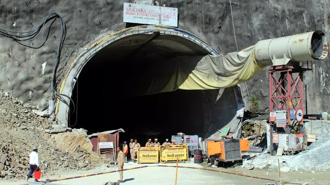 Menschen beobachten Rettungs- und Hilfsmaßnahmen an der Stelle eines im Bau befindlichen Straßentunnels, der im indischen Bundesstaat Uttarakhand eingestürzt ist. - Bild: Uncredited/AP/dpa
