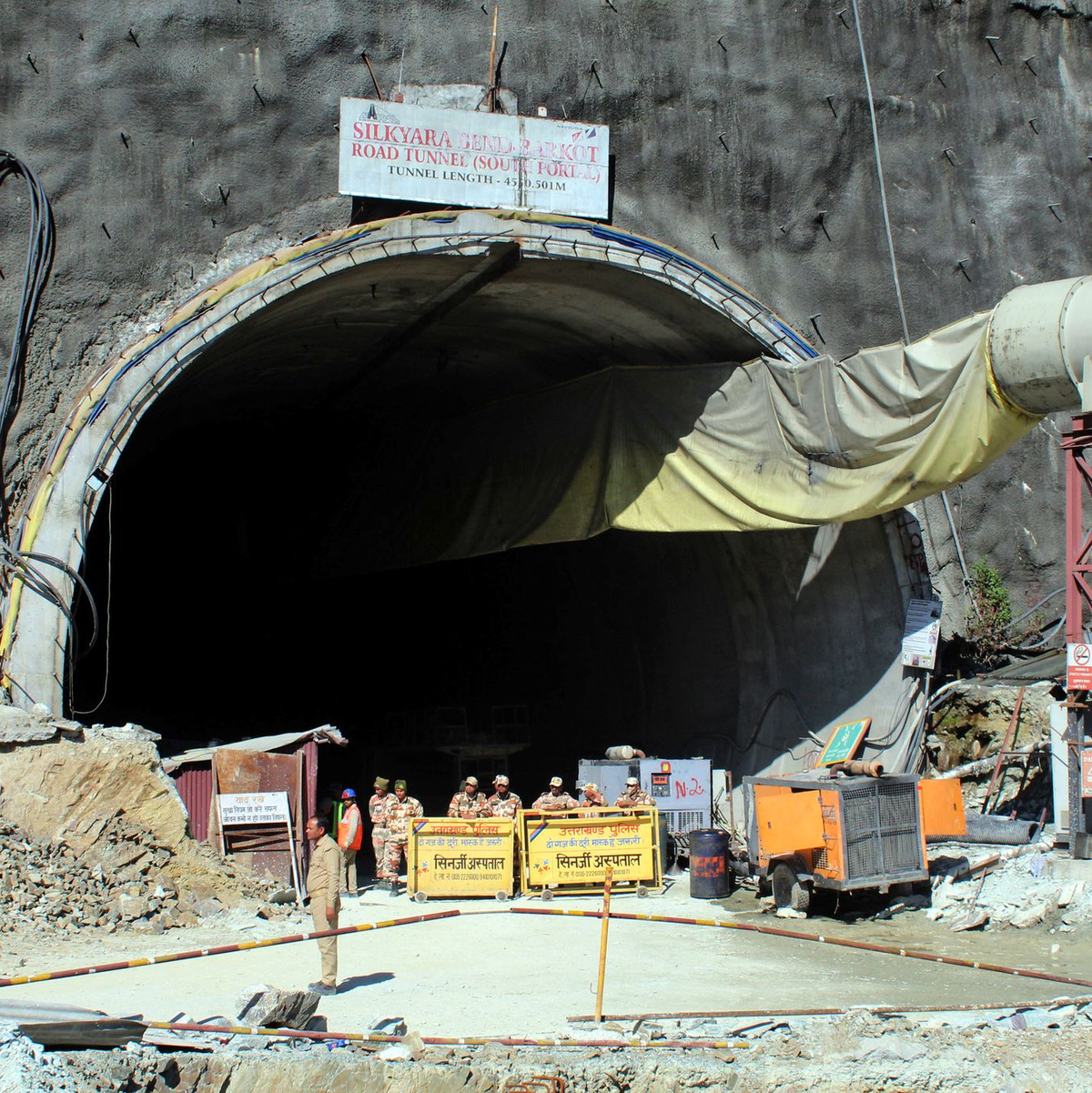 Menschen beobachten Rettungs- und Hilfsmaßnahmen an der Stelle eines im Bau befindlichen Straßentunnels, der im indischen Bundesstaat Uttarakhand eingestürzt ist. - Foto: Uncredited/AP/dpa