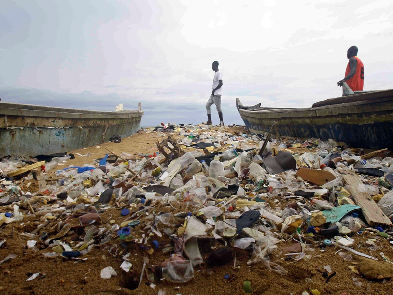 Menschen spazieren über einen mit Plastik verschmutzten Strand an der Elfenbeinküste. - Foto: Diomande Ble Blonde/AP/dpa