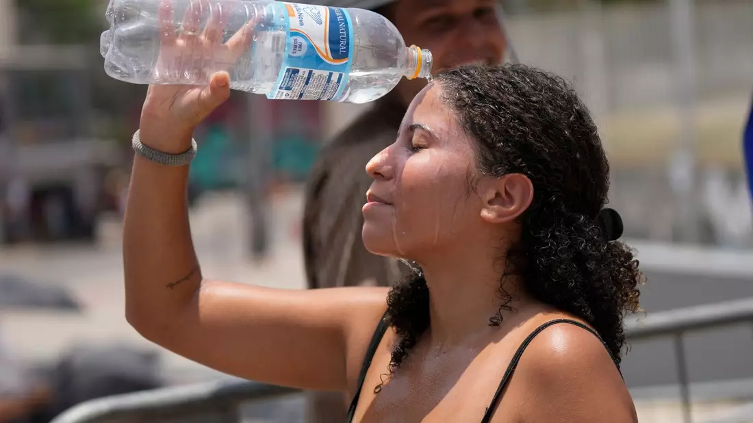 Ein Fan von Taylor Swift kühlt sich vor dem Konzert der «Eras»-Tour vor dem Olympiastadion in Rio de Janeiro mit Wasser ab. - Bild: Silvia Izquierdo/AP/dpa