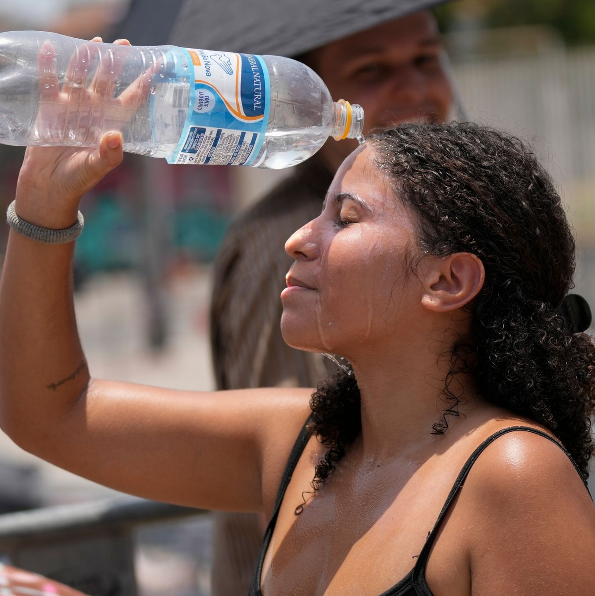 Ein Fan von Taylor Swift kühlt sich vor dem Konzert der «Eras»-Tour vor dem Olympiastadion in Rio de Janeiro mit Wasser ab. - Foto: Silvia Izquierdo/AP/dpa