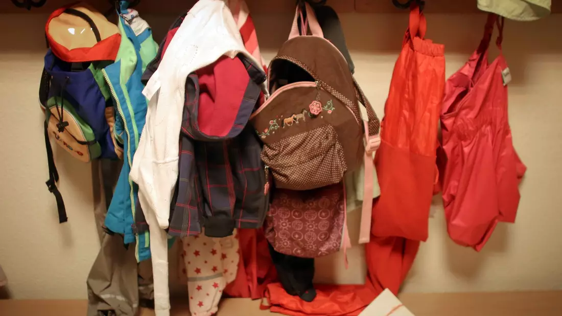 Jacken und Rucksäcke von Kindern in der Garderobe einer Betriebskita. - Bild: Fredrik Von Erichsen/dpa