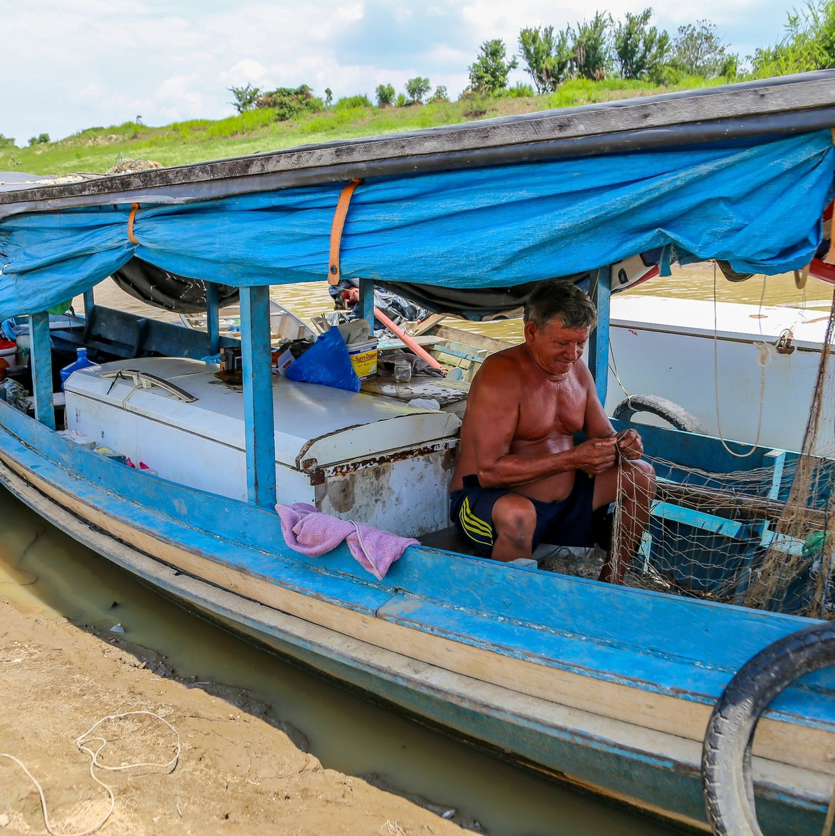 Ein Fischer sitzt fast im Trockenen in seinem Boot und flickt ein Netz. Die Dürre bereitet den Flussbewohnern nicht nur Schwierigkeiten beim Fischen, sondern auch beim Verkehr. Dörfer sind in der Region über die Flüsse vernetzt. - Foto: Aguilar Abecassis/dpa