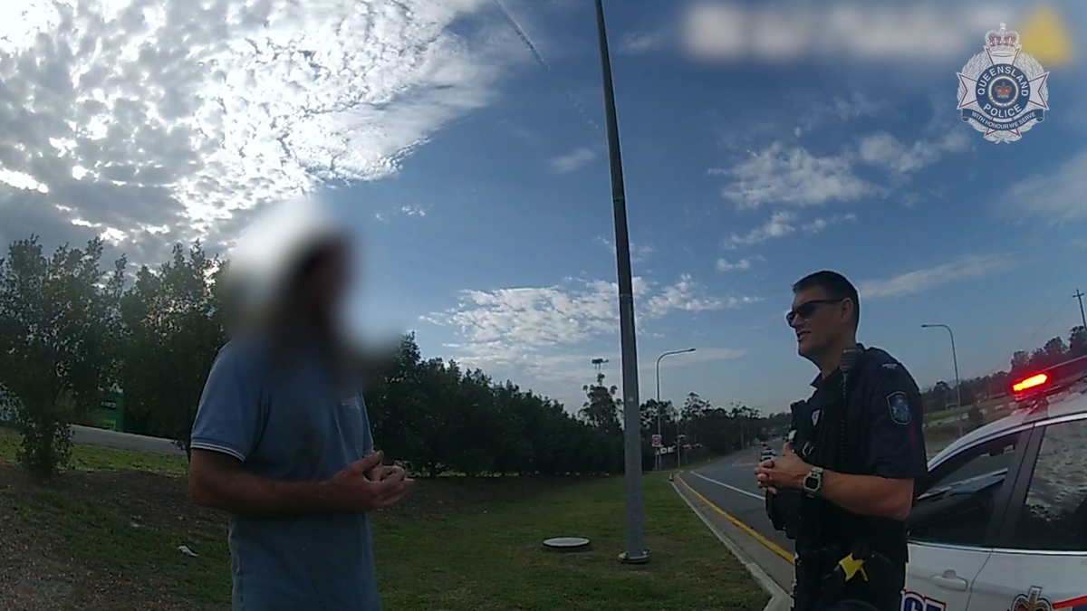Ein Videostandbild der Polizei Queensland zeigt den Mann im Gespräch mit einem Beamten. - Foto: Queensland Police/QUEENSLAND POLICE/AP/dpa