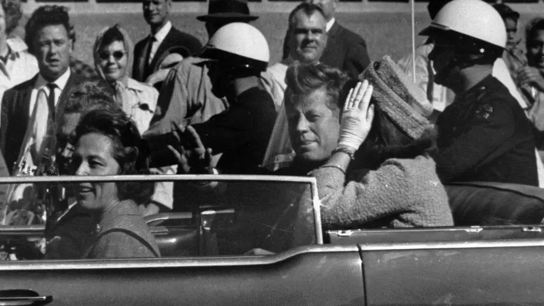 Kurz vor seiner Ermordung sitzt der damalige US-Präsident John F. Kennedy am 22.11.1963 in Dallas zusammen mit seiner Frau Jacqueline Kennedy (r) sowie dem dem Gouverneur von Texas, John Connally, und desen Frau Nellie Connally in einer offenen Limousine. - Bild: ---/AP/dpa