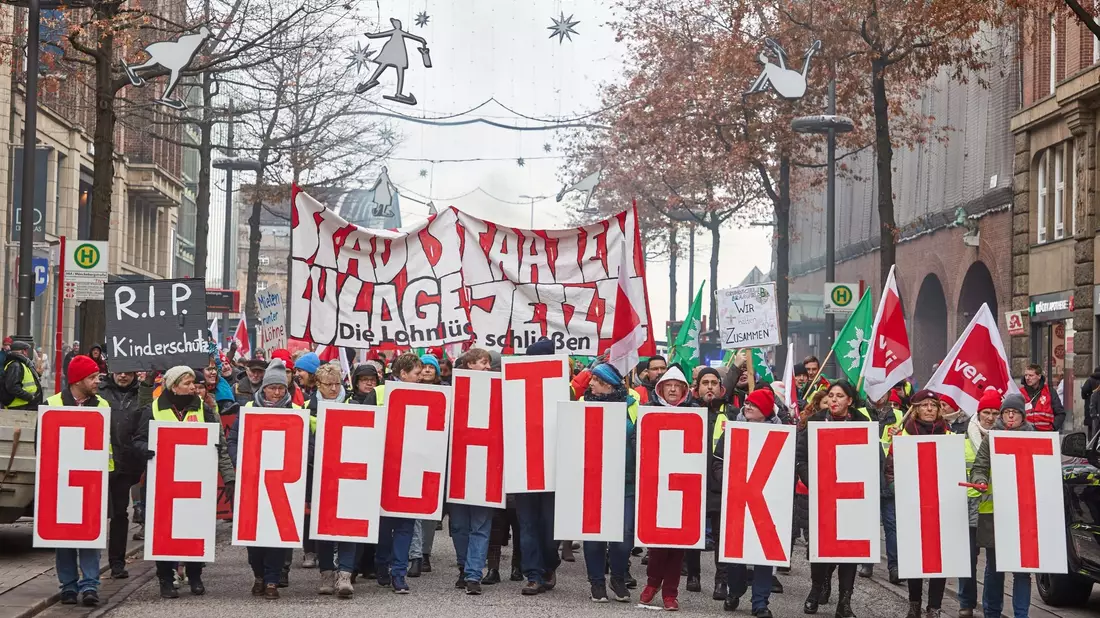 «Gerechtigkeit» - Teilnehmer ziehen beim «Stadtstaatenstreik» durch die Hamburger Mönckebergstraße. - Bild: Georg Wendt/dpa