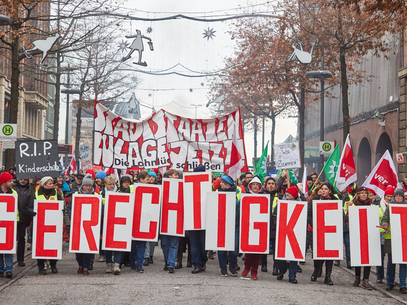 «Gerechtigkeit» - Teilnehmer ziehen beim «Stadtstaatenstreik» durch die Hamburger Mönckebergstraße. - Foto: Georg Wendt/dpa