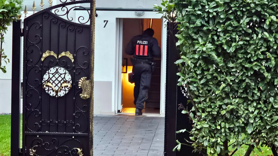 Ein Polizeibeamter geht bei einer Razzia in Bochum-Weitmar durch den Eingang eines Wohnhauses. - Bild: Markus Gayk/News Essen/dpa