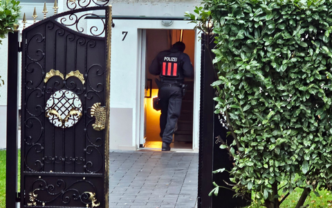 Ein Polizeibeamter geht bei einer Razzia in Bochum-Weitmar durch den Eingang eines Wohnhauses. - Foto: Markus Gayk/News Essen/dpa