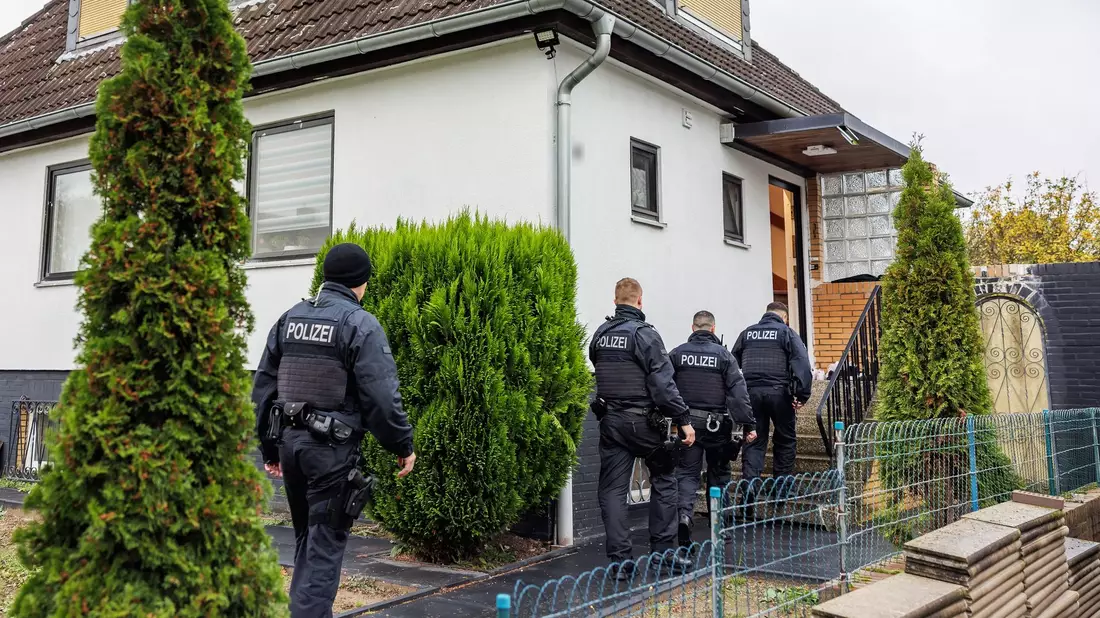Polizeibeamte durchsuchen ein Haus in einer Wohnsiedlung in Garbsen. - Bild: Ole Spata/dpa