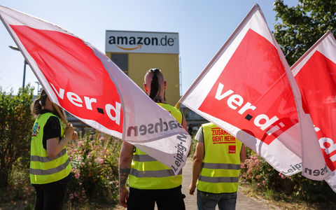 Streikende stehen mit Verdi-Flaggen vor einem Verteilzentrum des Online-Händlers Amazon in Leipzig (Archivbild). - Foto: Jan Woitas/dpa