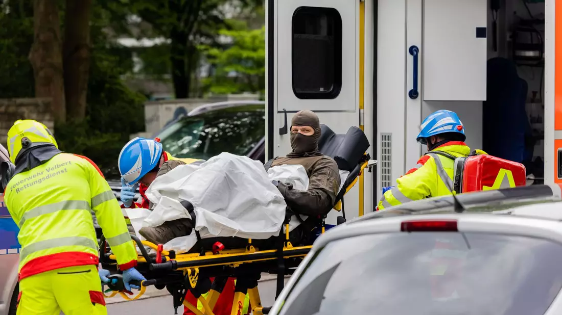 Ein verletzter Polizeibeamter wird vor einem Hochhaus in einen Krankenwagen gebracht. - Bild: Rolf Vennenbernd/dpa