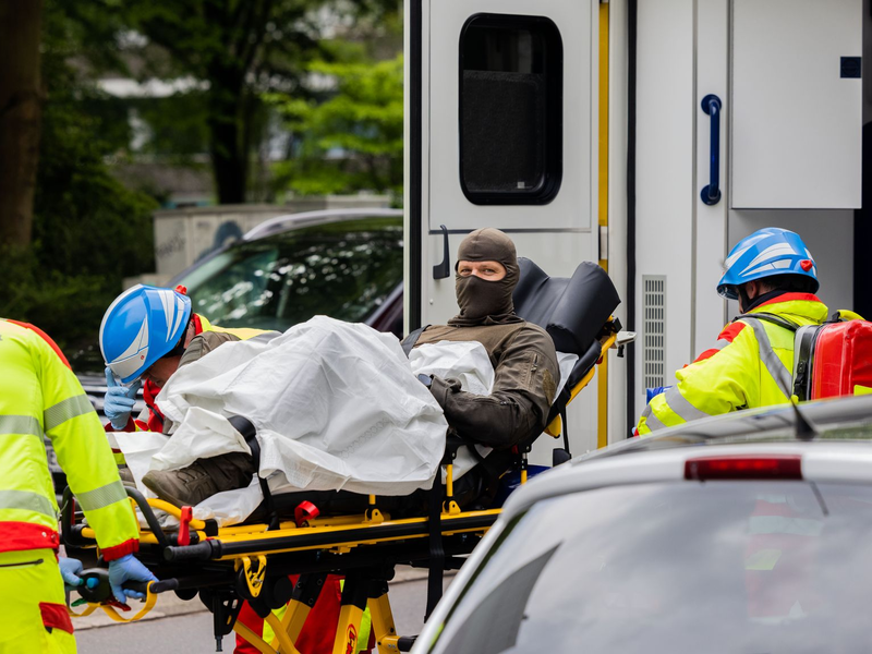 Ein verletzter Polizeibeamter wird vor einem Hochhaus in einen Krankenwagen gebracht. - Foto: Rolf Vennenbernd/dpa