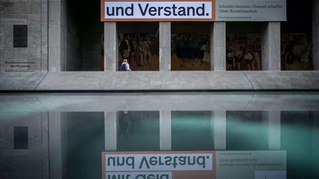 Ein Plakat mit der Aufschrift «Mit Geld und Verstand. Schulden bremsen, Chancen schaffen. Unser Bundeshaushalt» hängt über dem Eingang zum Bundesministerium der Finanzen in Berlin. - Bild: Kay Nietfeld/dpa
