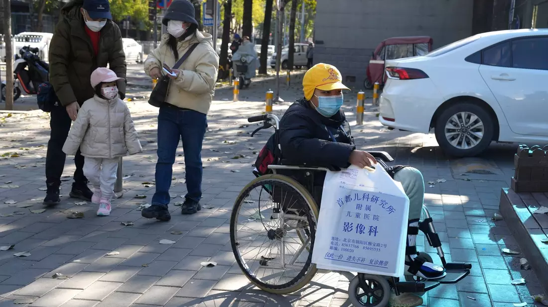 Ein Junge in einem Rollstuhl hält in Peking eine Tasche aus der radiologischen Abteilung eines Kinderkrankenhauses. In den vergangenen Tagen hatten Berichte über die starke Häufung von Atemwegserkrankungen bei Kindern Sorgen aufkommen lassen. - Bild: Ng Han Guan/AP/dpa