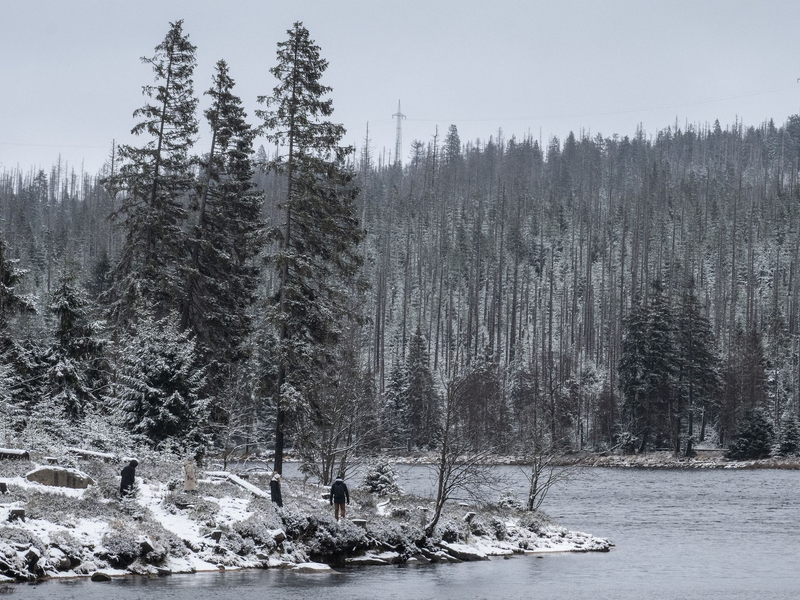 Wanderer gehen am leicht verschneiten Oderteich im Harz spazieren. - Foto: Swen Pförtner/dpa