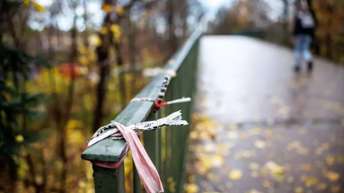 Der Rest eines Absperrbands der Polizei am  Geländer einer Fußgängerbrücke im Englischen Garten in München. Dort kam das Opfer zu Tode. - Bild: Matthias Balk/dpa