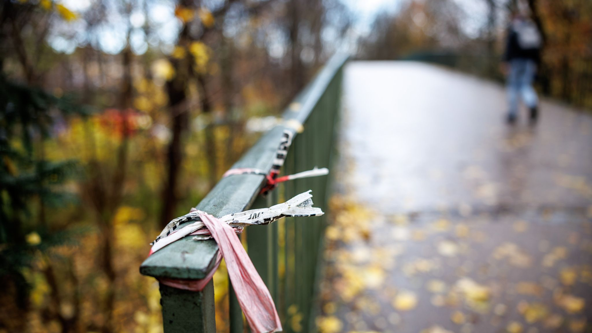 Der Rest eines Absperrbands der Polizei am  Geländer einer Fußgängerbrücke im Englischen Garten in München. Dort kam das Opfer zu Tode. - Foto: Matthias Balk/dpa